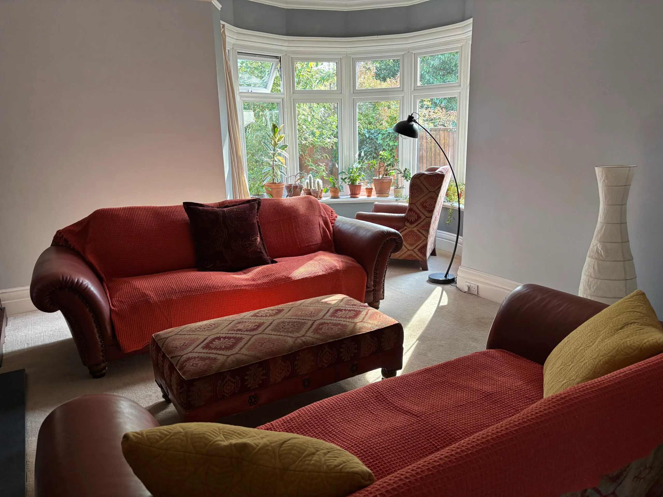 Comfortable counselling room with red sofas and a bay window